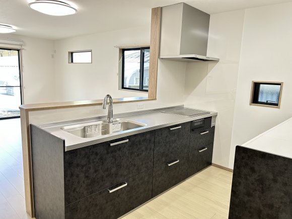 ∼夫婦で楽しむ、開放感たっぷりのキッチン∼

リビングを見渡せる対面キッチンは、家族の会話が自然に生まれる設計。
高さ90cmでご主人も使いやすく、夫婦で並んで料理を楽しめます。背の高いカップボードは収納力があり、調理器具や食器をすっきり整理可能。常に片付いた空間を保てます。
さらにタッチレス水栓を備え、衛生面にも配慮。家族の時間と快適さを両立した理想のキッチンです。