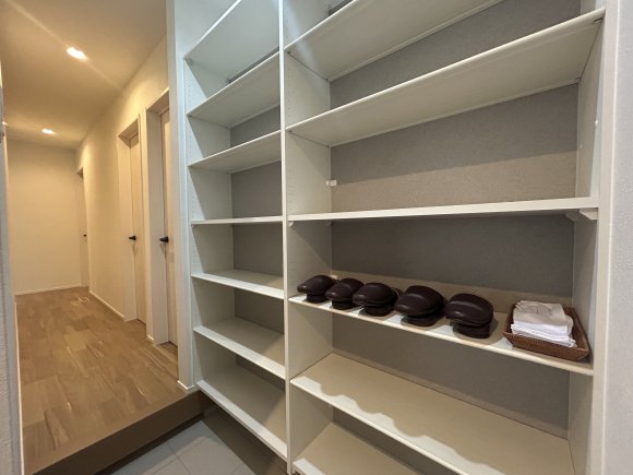 ∼大容量のシューズクローゼット∼

玄関横には、たっぷり収納できる大容量のシューズクローゼットを設置。
可動棚付きなので、ブーツやスニーカーなど靴の高さや数に合わせて自由に調整できます。
土間仕様になっているため、アウトドア用品やお子様の遊び道具など、外で使うアイテムもそのまま収納可能。
外の汚れを室内に持ち込まずに済み、いつでも清潔で整った玄関を保てます。
家族が多くても靴や荷物が散らからず、見た目も機能もスマートな収納空間です。

※画像はイメージです