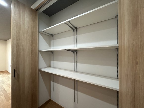 リビングやキッチンに物を溢れさせない秘訣は、この奥行きのある可動棚収納。生活スタイルに合わせて棚の高さを自由に変えられるため、掃除機などの大型家電から、日々の書類、ストック品まで効率よく収まります。扉を閉めれば壁のようにフラットになり、生活感を一瞬でリセットできる設計です。