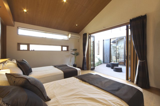 大開口で中庭とつながる寝室は、勾配天井も相まってとても開放的。
建材やファブリックを低めの色調でまとめて、落ち着いたイメージに仕上げました。