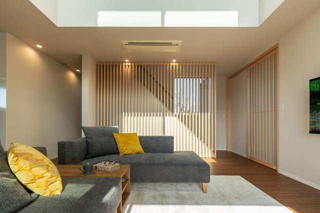 開放的な吹き抜けから暖かな陽光が差し込むLDKがアクセントとなり、階段部に設けた木のスリットが目を引きます。