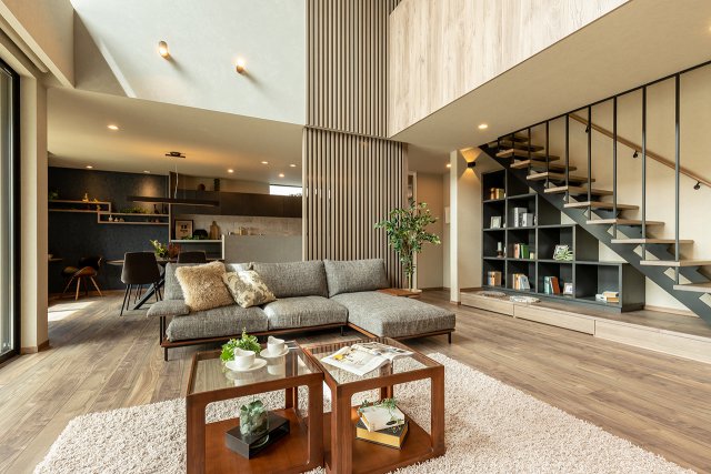 吹き抜けから降り注ぐ自然光の優しい明るさに満ちたLDK。2階まで続く木製ルーバーがアクセントになり、開放的な空間を引き締めています。