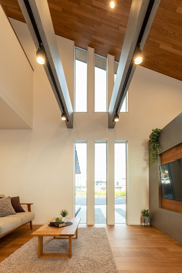 子世帯のリビングは高天井とし、そこに勾配を設けました。木目の突板とコンクリート調の見せ梁で調和のとれた空間を演出しています。