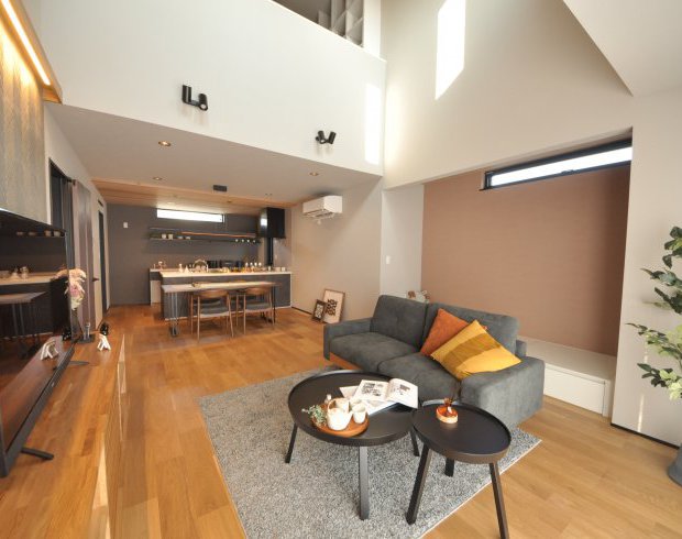 吹き抜けを採用した開放感のあるLDK。ウォールナットのぬくもりとグレートーンのインテリアでホテルライクな印象に。リビングスペースに設けたヌックスペースが抜け感を演出します。