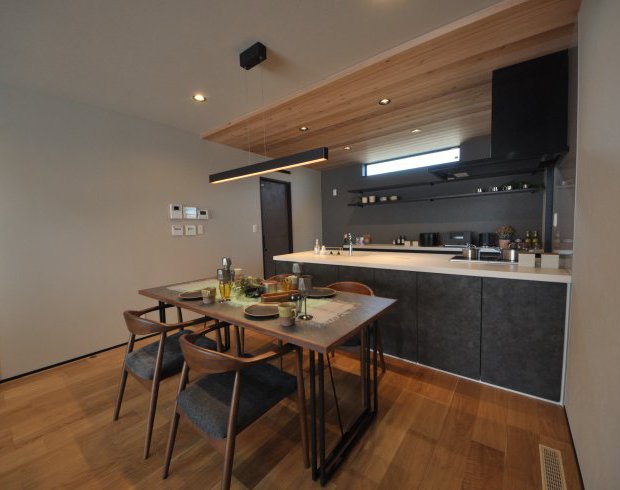 グレートーンのペニンシュラキッチン。家族とのつながりを大切にするために、普段使いする機会が多いキッチンとダイニングをフラットに繋げるデザインにしています。