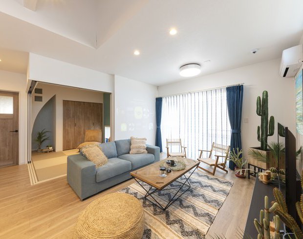 大きな窓からたっぷりと自然光が差し込むリビングは、観葉植物やナチュラル素材の家具が調和した、癒しとくつろぎの空間です。