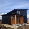 薄くシャープに伸びた片流れの屋根、黒の金属サイディングと木目のテクスチャの対比が美しいキノイエ
