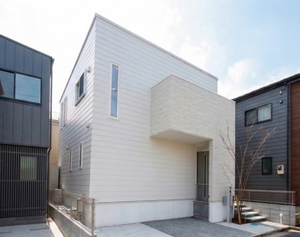 白を基調とした外観に、飾りすぎないすっきりとしたデザインが映える住まい。
玄関へ続くおしゃれなアプローチが印象的で、扉を開けても室内が見えにくいよう配慮された設計です。