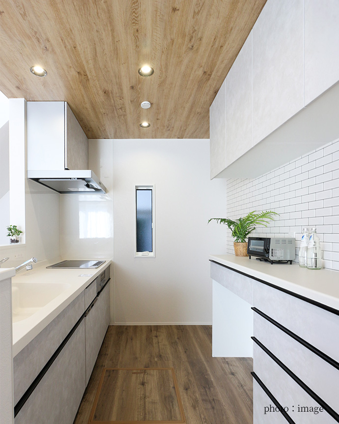 木目天井と白いタイルがおしゃれな白のシステムキッチ