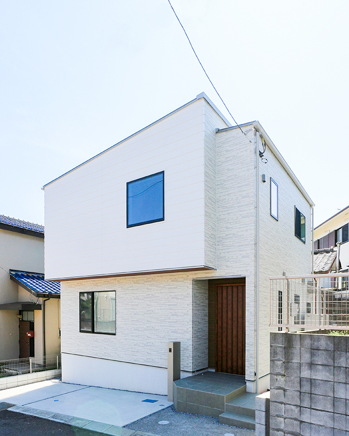 白壁にスクエア窓と木目扉が映える戸建