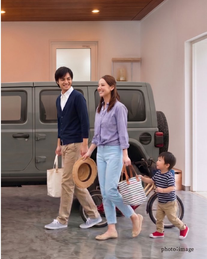 木目調天井のガレージハウスに駐車された車と、その横を歩く家族